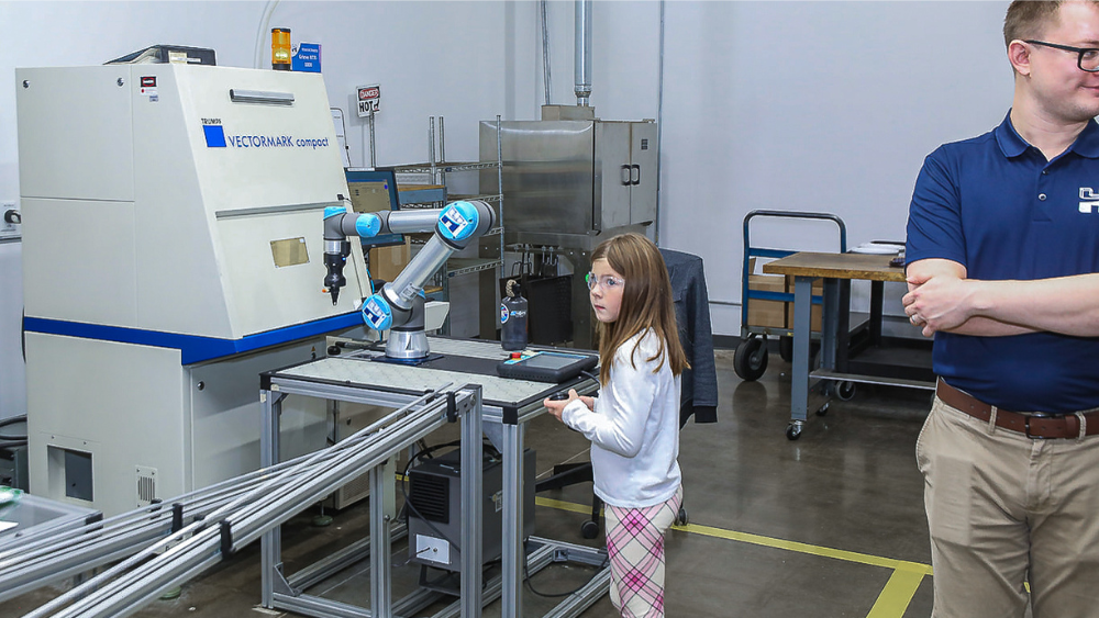 Young girl looks at cobot lasermarking parts