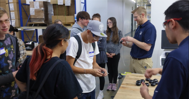 Students look at parts lasermarked by a robot