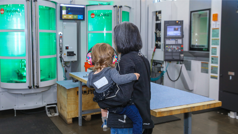 Young girl and mother look at automated manufacturing center